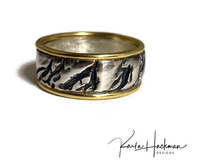 Hand carved in wax and cast in sterling silver, this hand-fabricated ring is edged in solid 18 karat gold on both sides.  Ring is given an oxidized finish to highlight the abstract, natural organic texture.