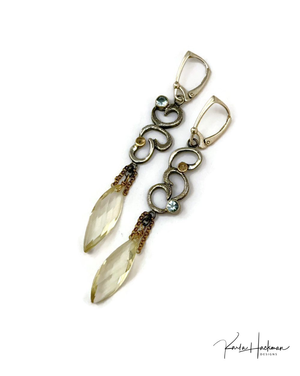 Gold and silver earrings with light yellow gemstones on a white background