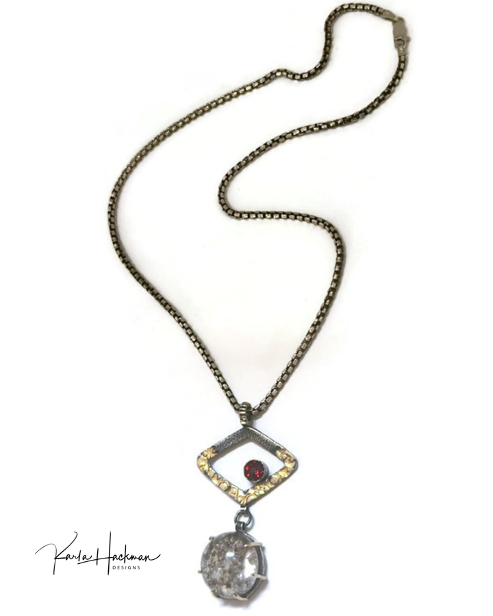 Necklace with a pendant featuring a red gemstone and clear crystal with internal texture on a white background.