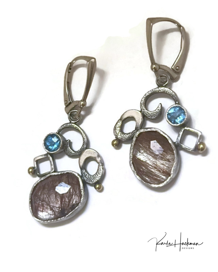 Pair of earrings with brown and blue gemstones on a white background