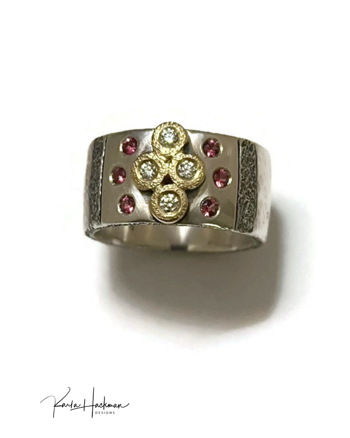 Silver ring with gold, diamond, and pink gemstone accents on a white background.