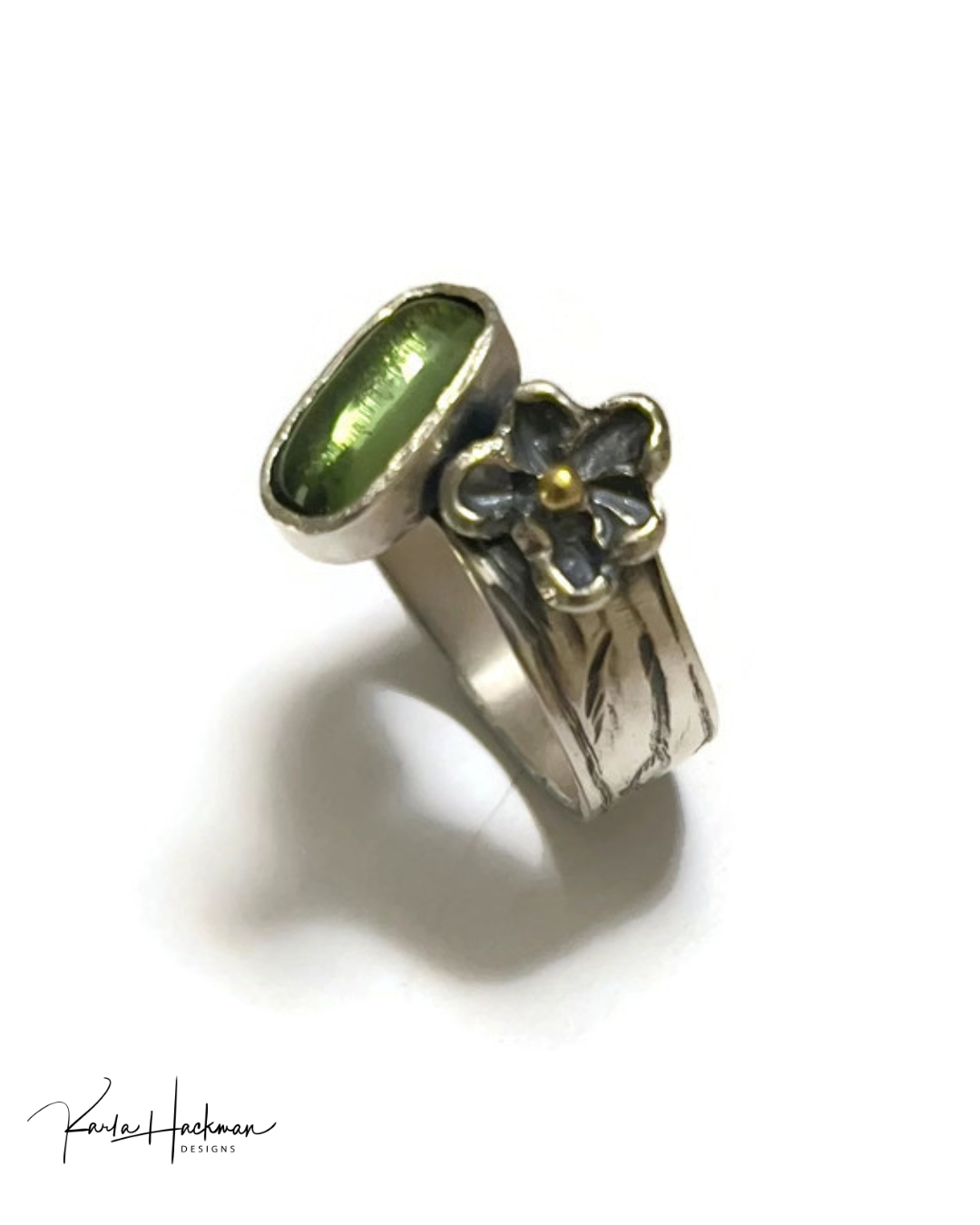 Silver ring with green gemstone and floral design on a white background