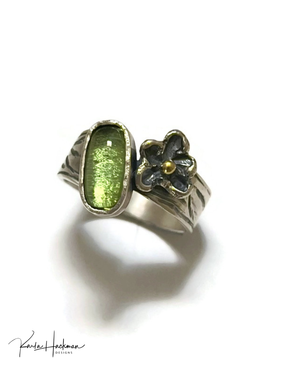 Silver ring with green stone and floral design on a white background