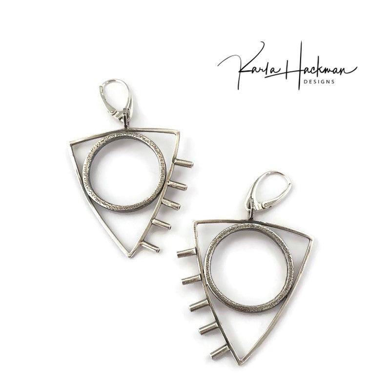 These earrings are a little rock and roll and a whole lot of fun! Large sterling silver, textured circles are surrounded by triangles and finished with tube accents. Earrings are lightly oxidized and finished with lever backs. Solid sterling silver.